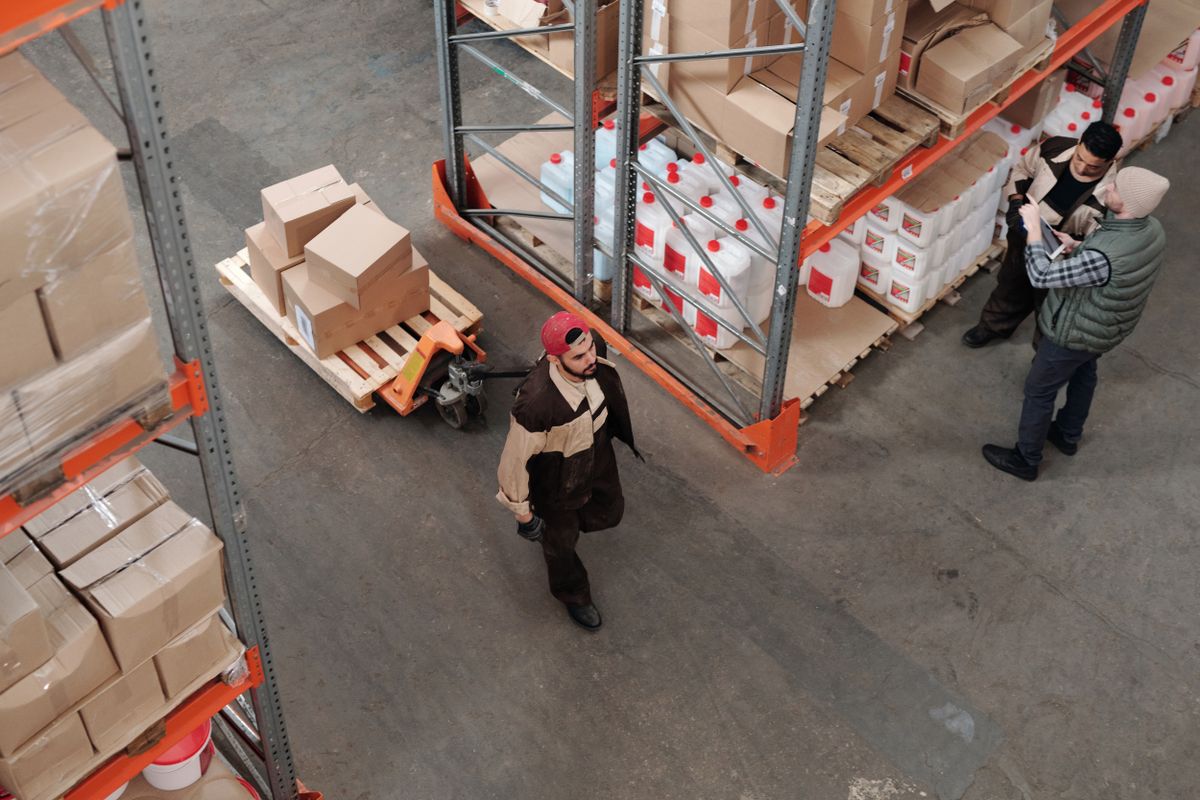 Warehouse team moving palletised stock with a pallet jack for dispatch